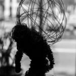 Wire figure sculpture with abstract design in monochrome, evoking thoughtful contemplation.
