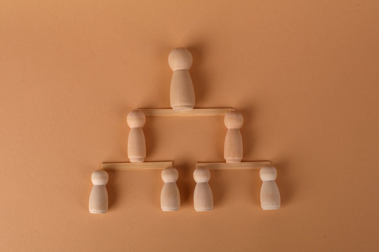 Wooden peg dolls arranged in a pyramid, symbolizing leadership and teamwork.