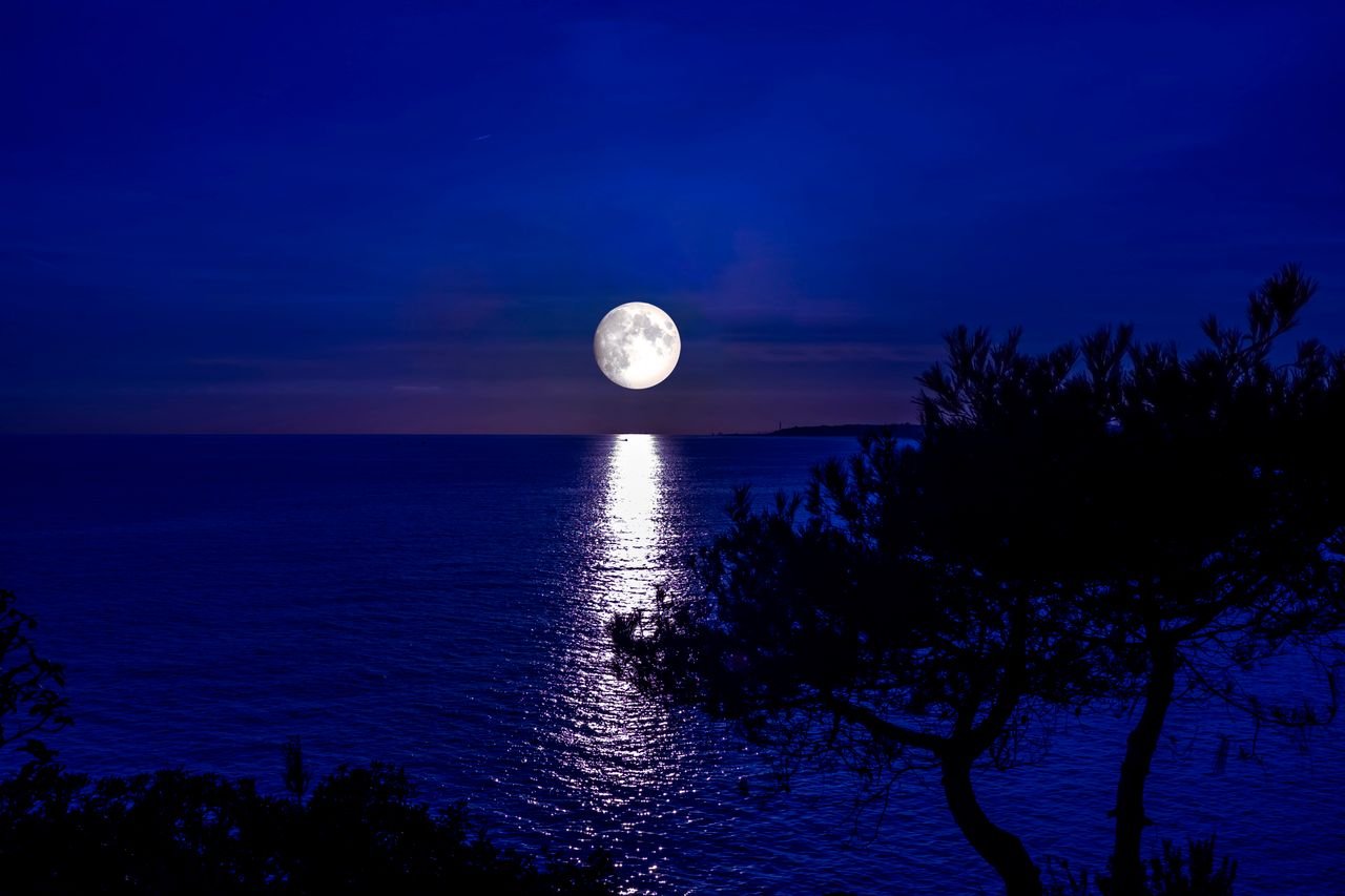 A stunning view of the full moon reflecting on the sea at Roda de Berà, Spain.