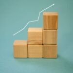 Wooden blocks forming a staircase with an upward arrow symbolizing growth and progress.